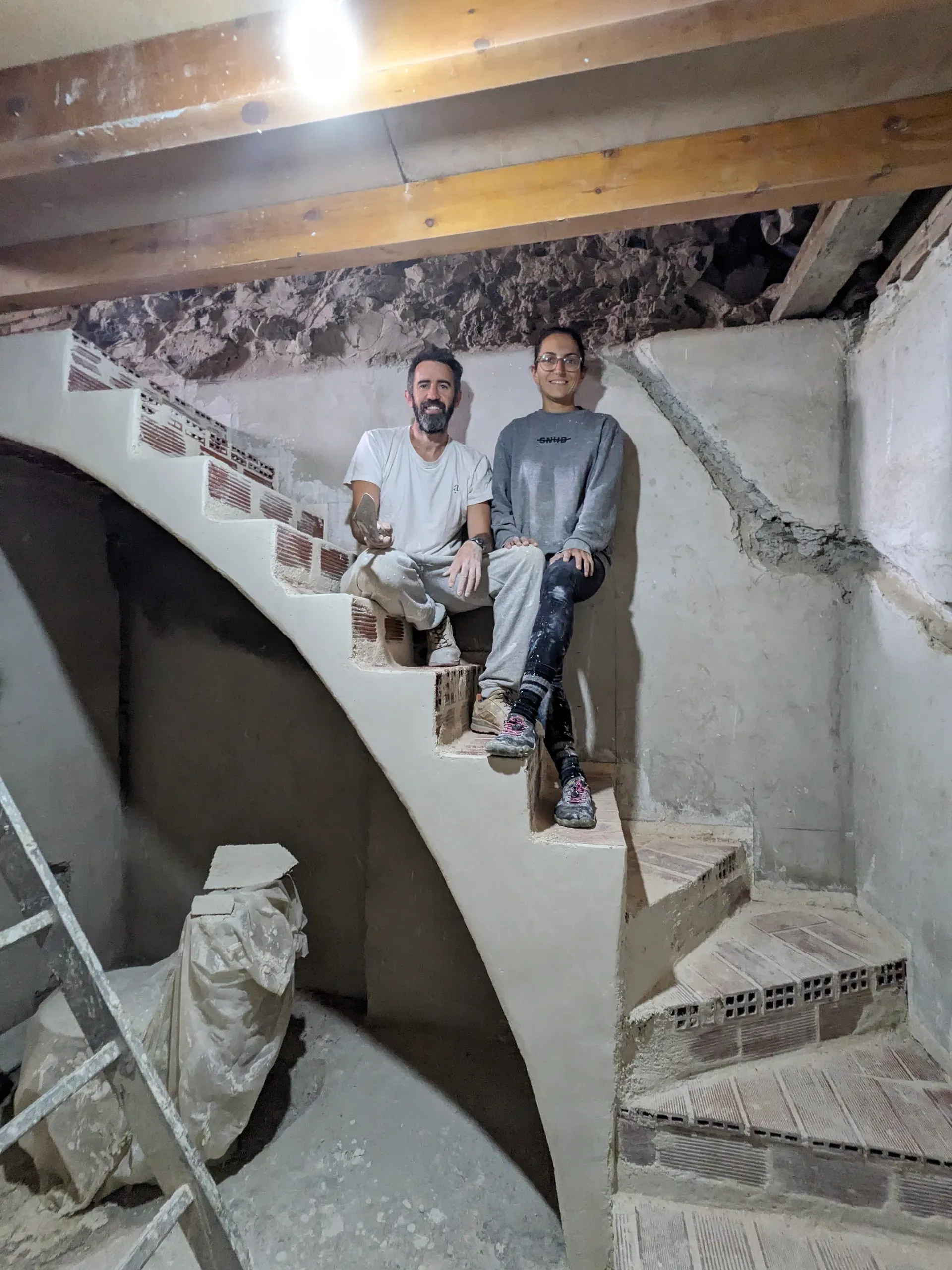 Equipo de obra posando en la escalera en fase de revestimiento, mostrando la geometría orgánica de la estructura