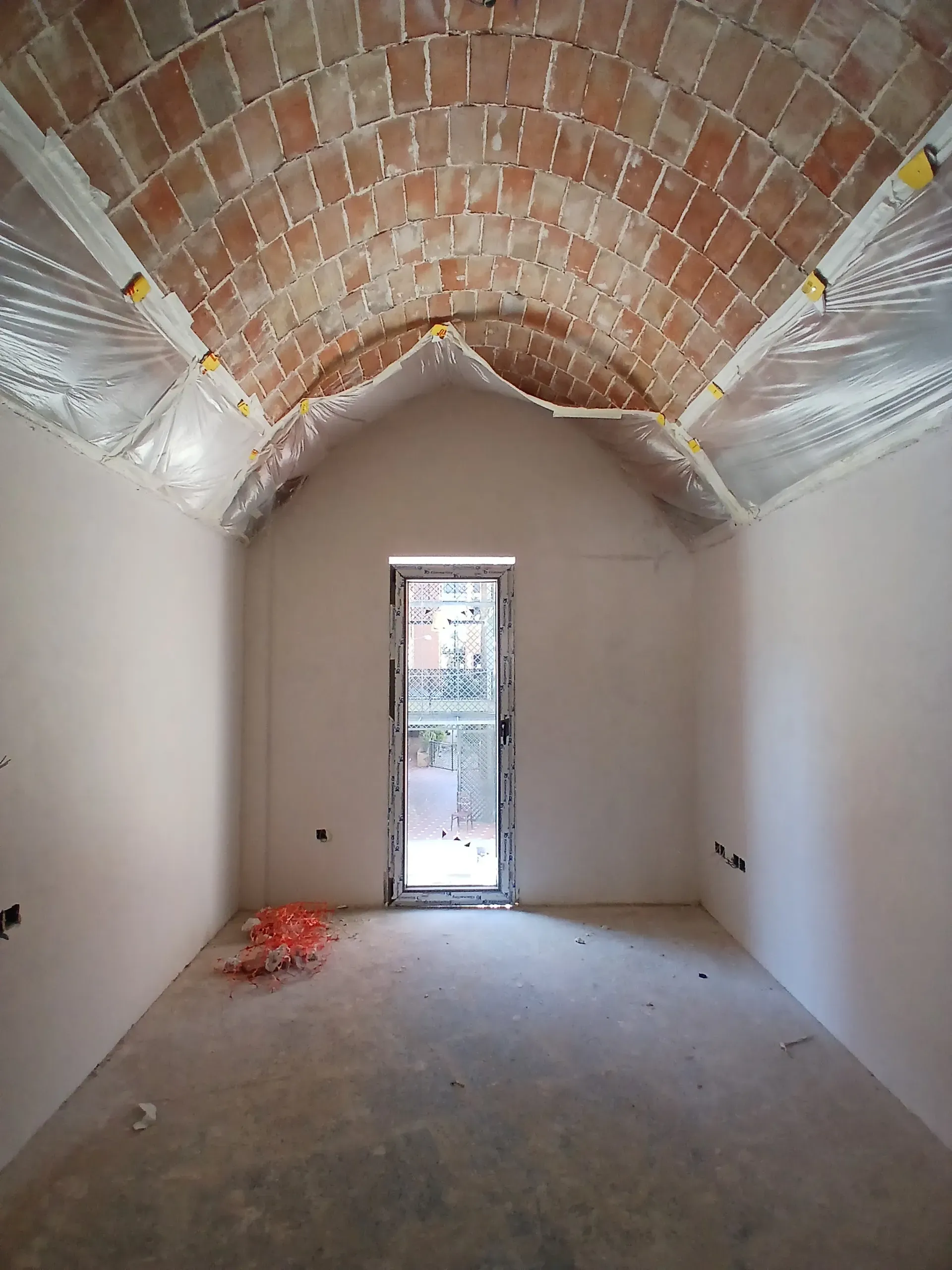 Luz natural bañando una estancia de paredes blancas bajo la calidez geométrica de una bóveda.