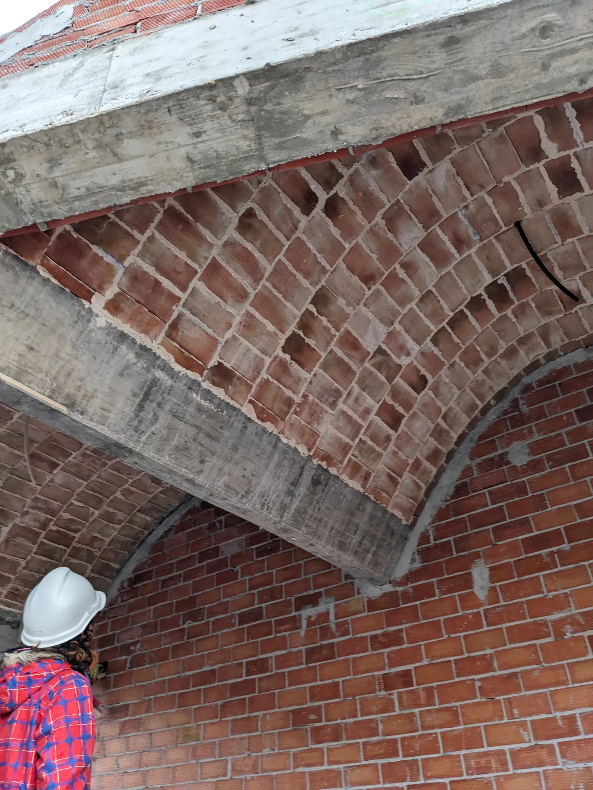 Detalle técnico de la colocación del ladrillo bajo una viga de hormigón contemporánea.