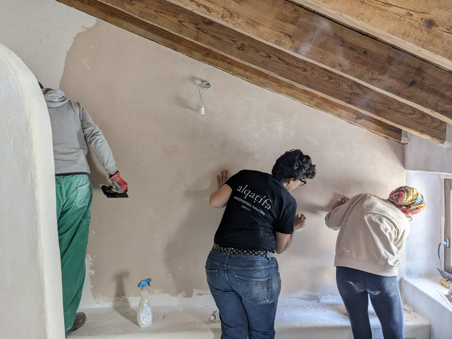 Equipo de Alqatifa aplicando revoco de cal bajo la cálida estructura de madera original