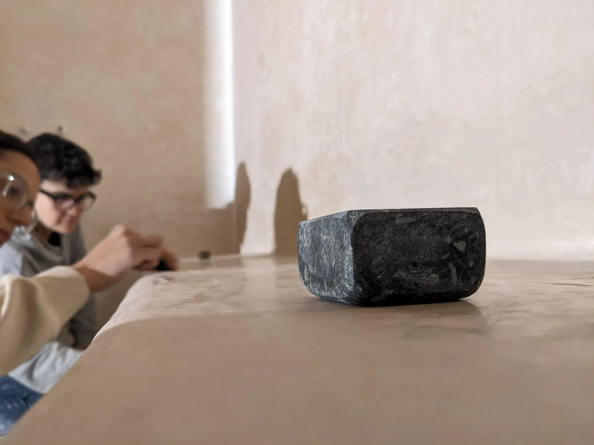 Piedra de pulido sobre la superficie sedosa del tadelakt, revelando el brillo mineral