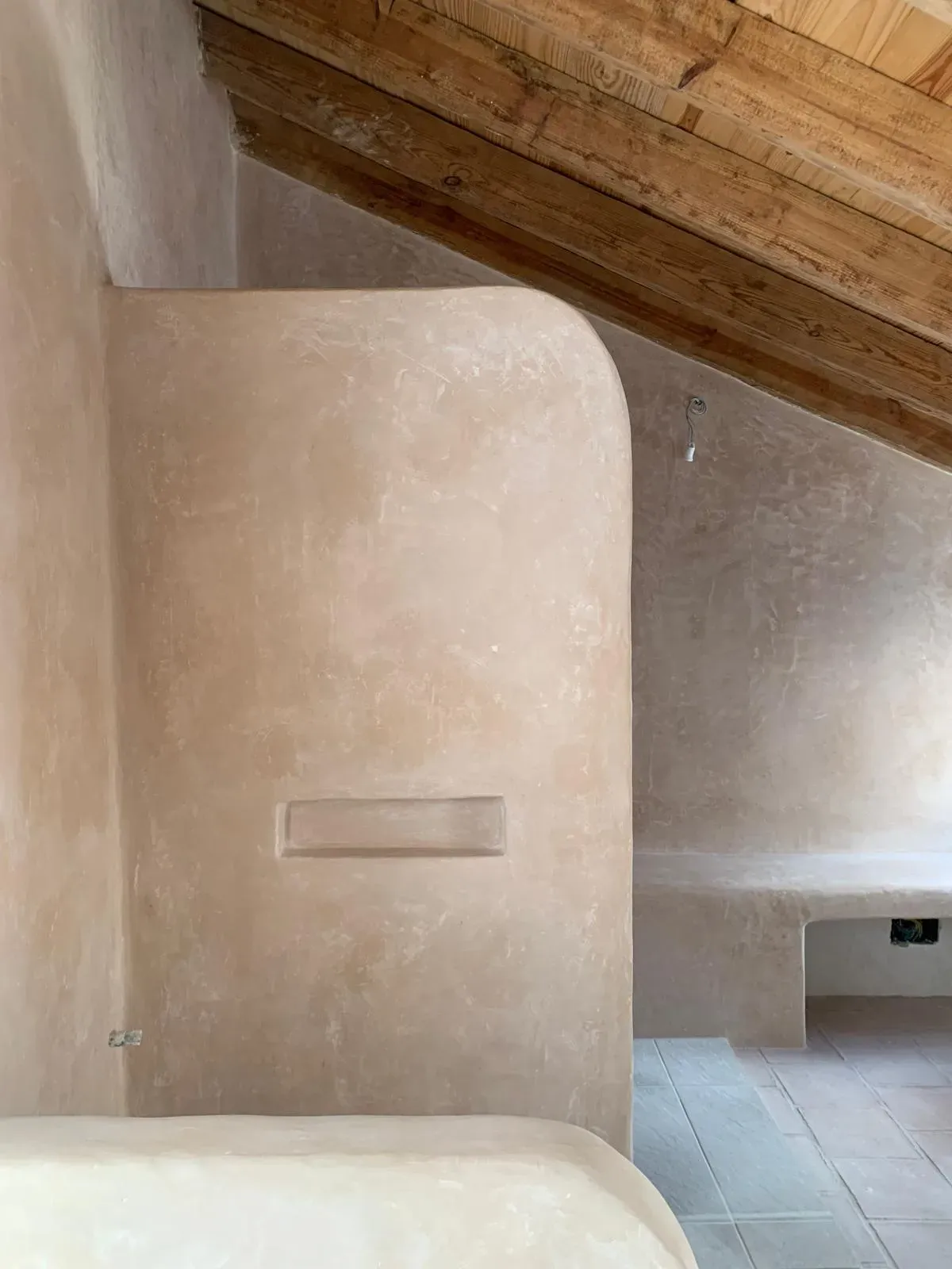 Formas orgánicas y curvas en tadelakt que esculpen el espacio bajo la cubierta inclinada