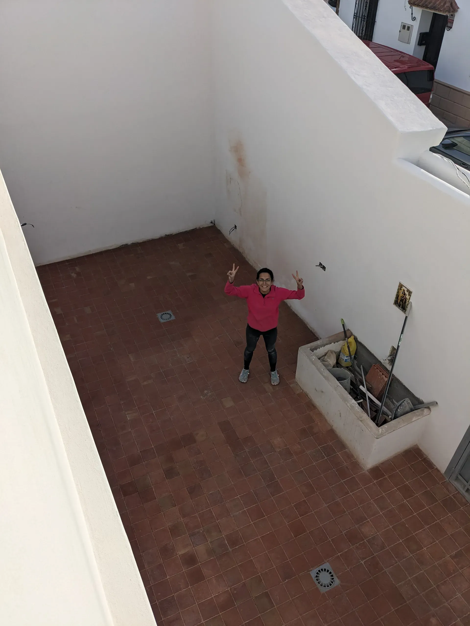 Vista cenital de patio con suelo de terracota recuperado y María José celebrando