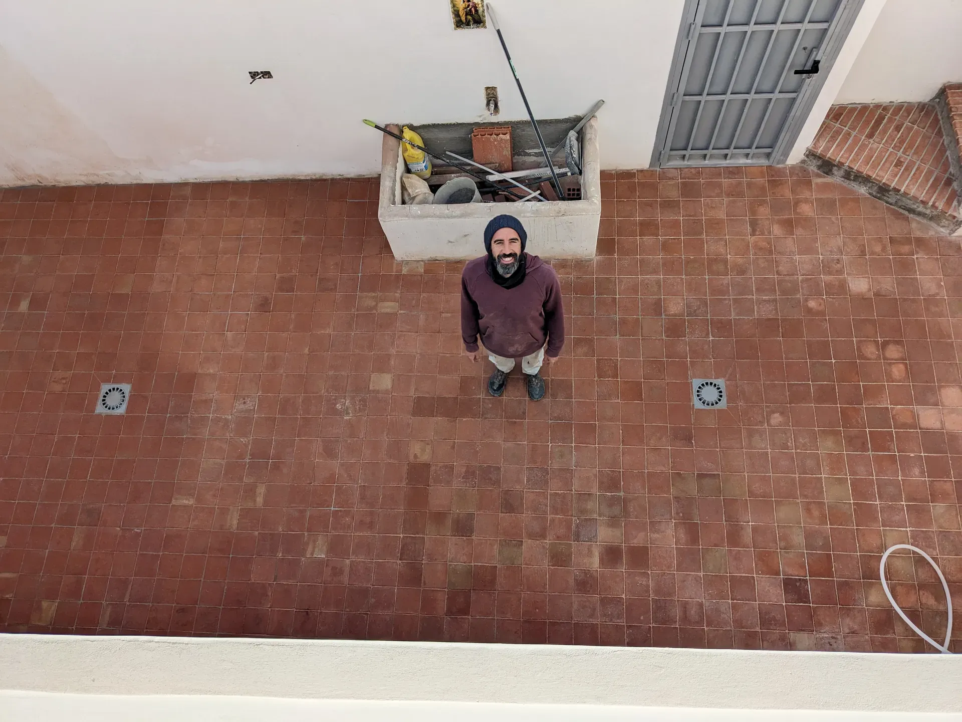 Vista aérea de artesano en patio solado con baldosas de barro cocido