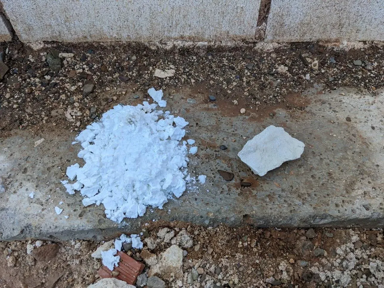 Contraste visual entre cal en polvo hidratada y un fragmento de cal viva en roca