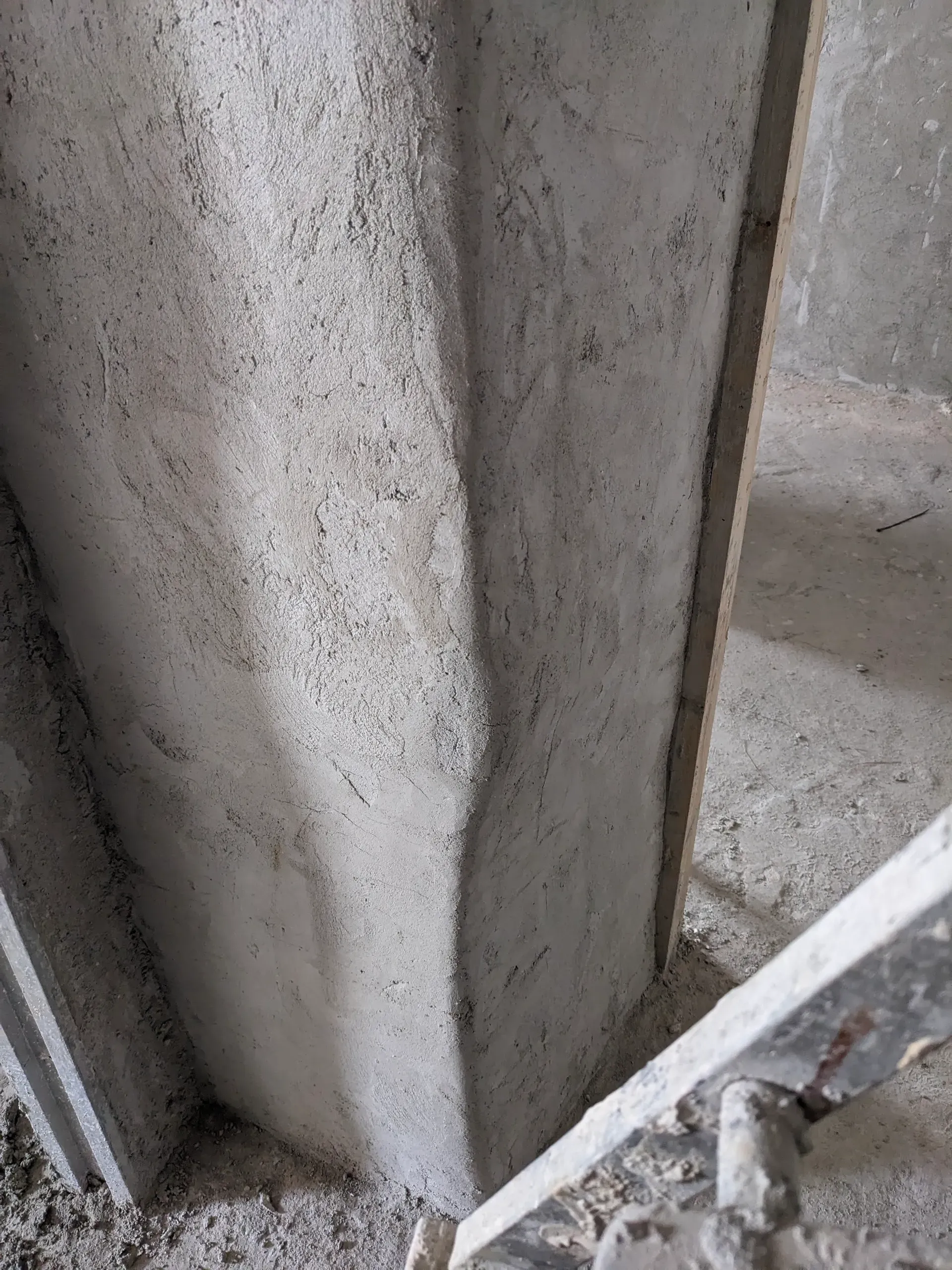 Primer plano de una arista curva de un muro revocado en cal, mostrando la suavidad de las formas orgánicas