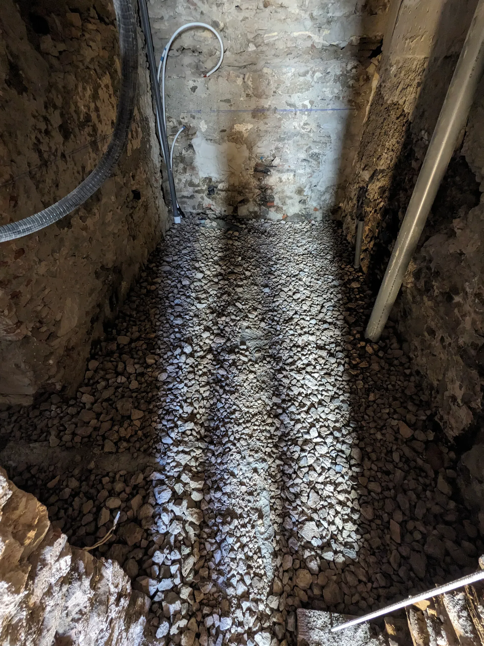 Vista en perspectiva de la base de la solera rellena de grava para drenaje y ventilación en el interior de una vivienda rehabilitada