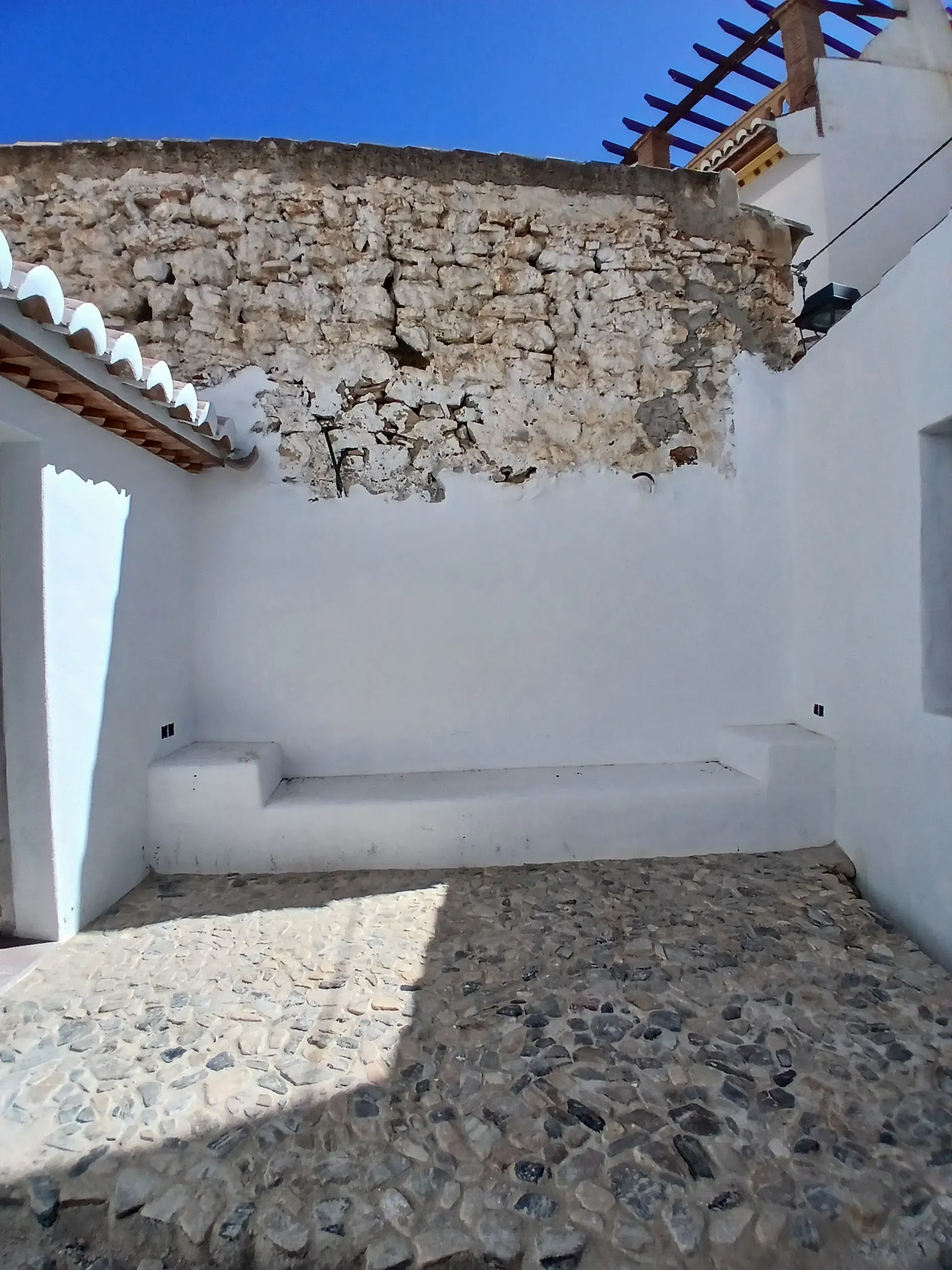 Resultado final del patio con el empedrado vernáculo ejecutado y banco de obra integrado