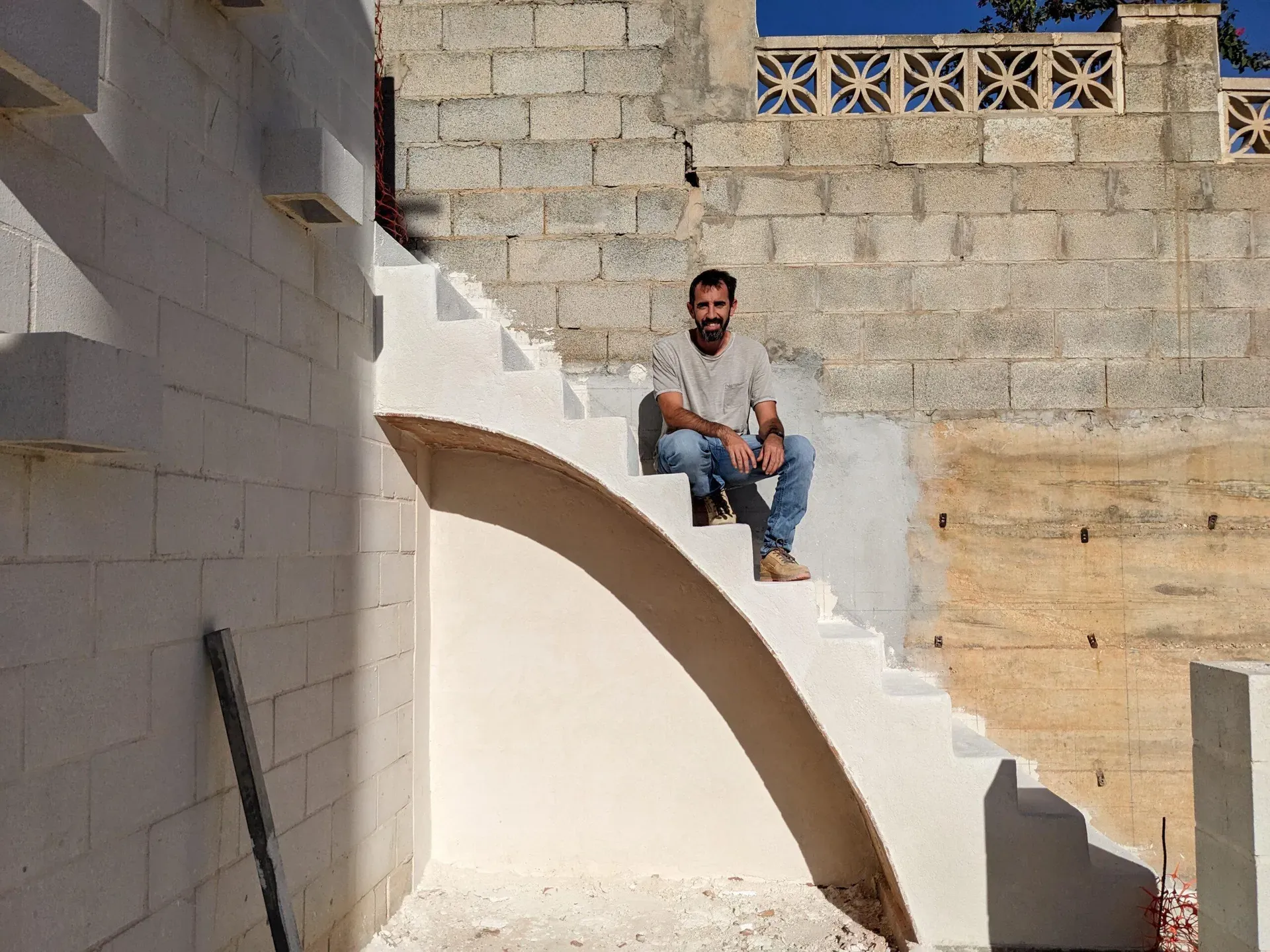 Jesús sentado en la escalera terminada, mostrando la solidez y elegancia de la construcción tradicional