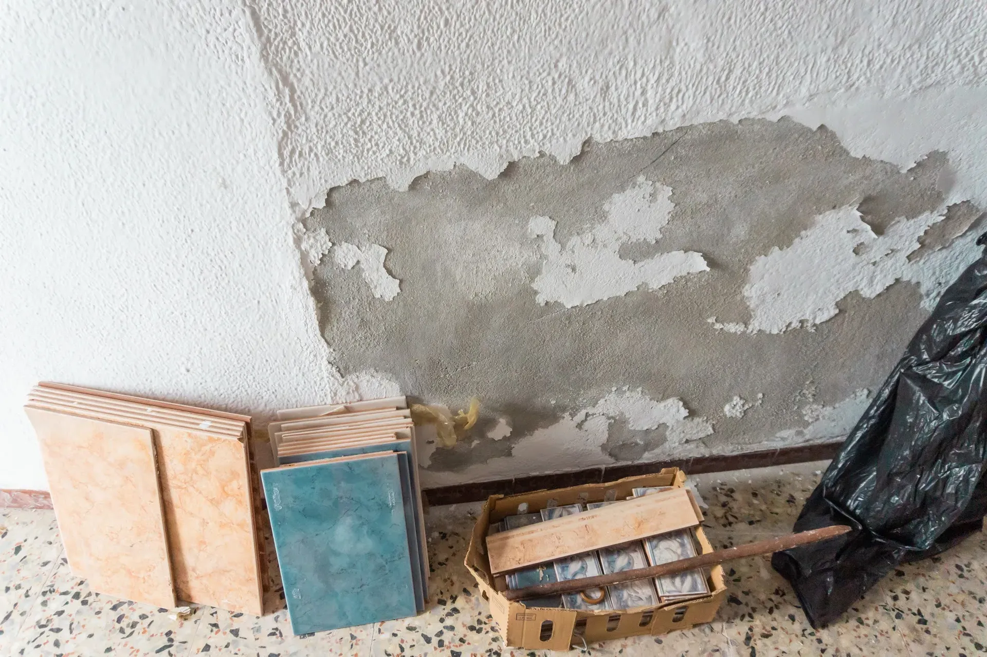 Detalle de eflorescencias salinas en un muro de mampostería asfixiado por pintura plástica y mortero de cemento