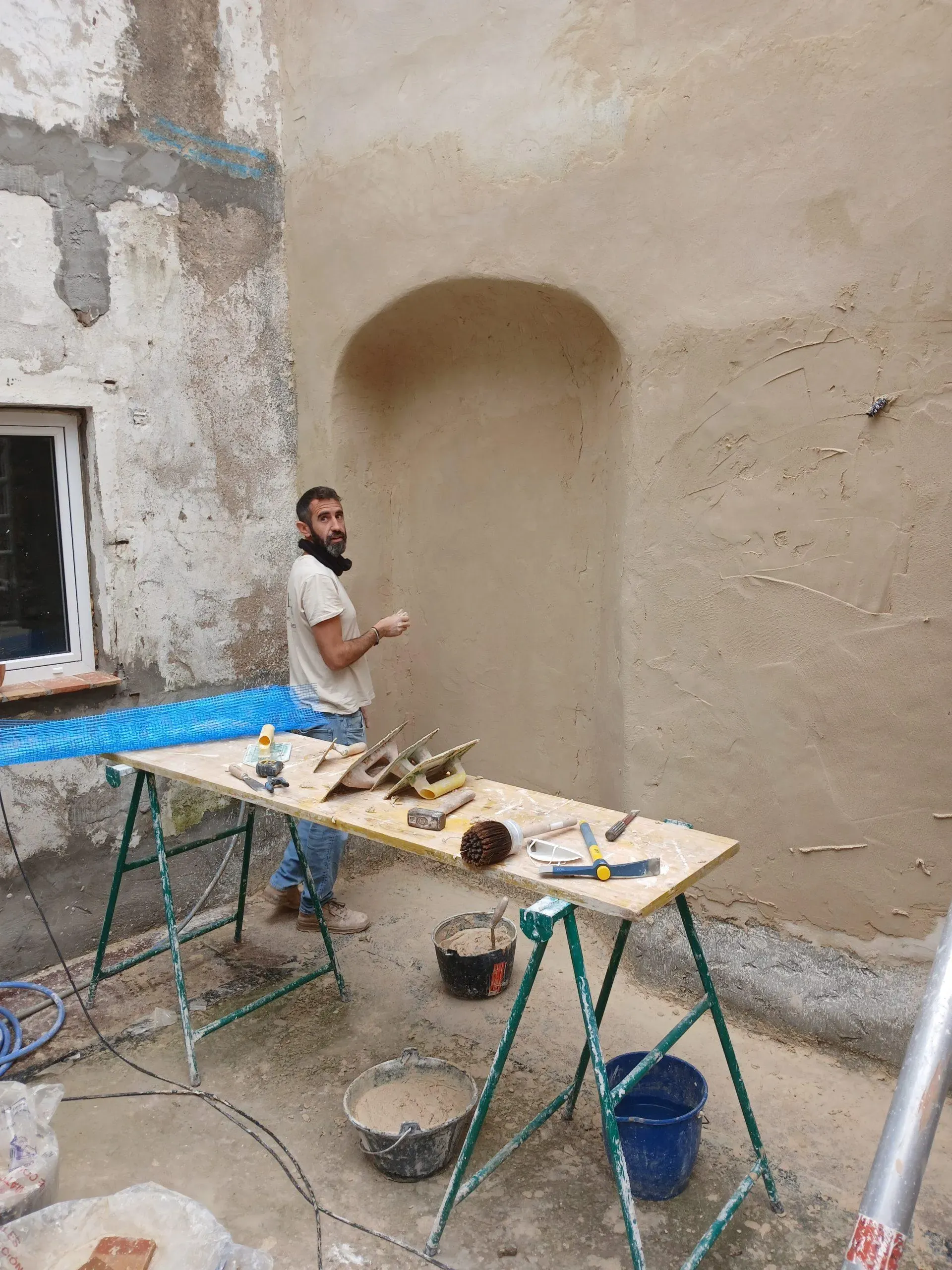 Jesús Moral preparando herramientas frente a una hornacina revestida con mortero de cal