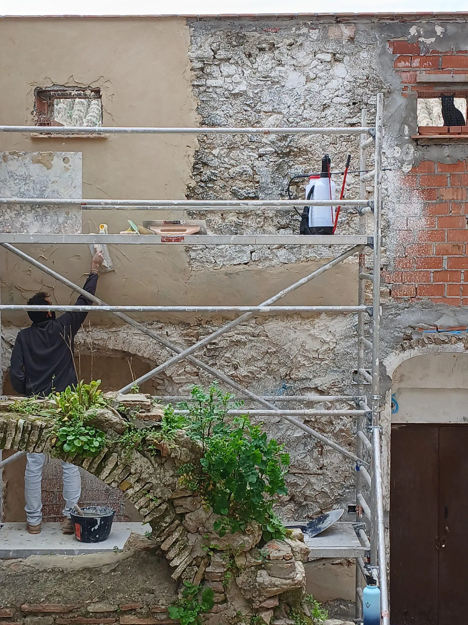 Application of lime mortar on old facade, consolidating masonry with traditional techniques