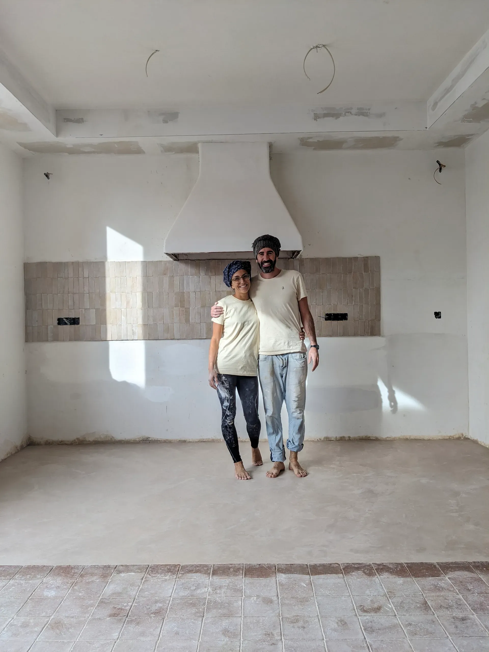 Pareja de artesanos posando en la cocina finalizada con el nuevo pavimento