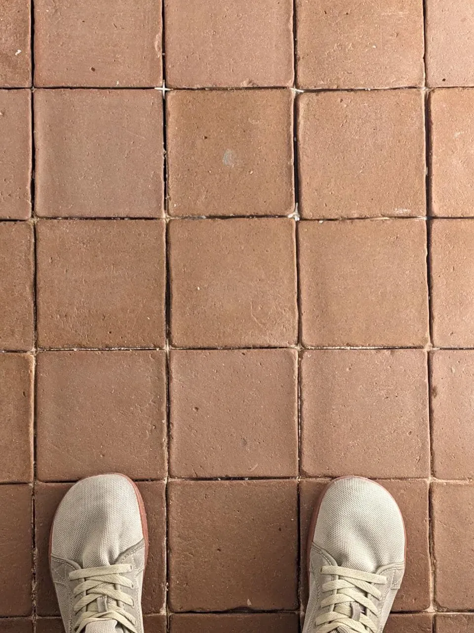 Installer working on clay floor, applying lime mortar between joints