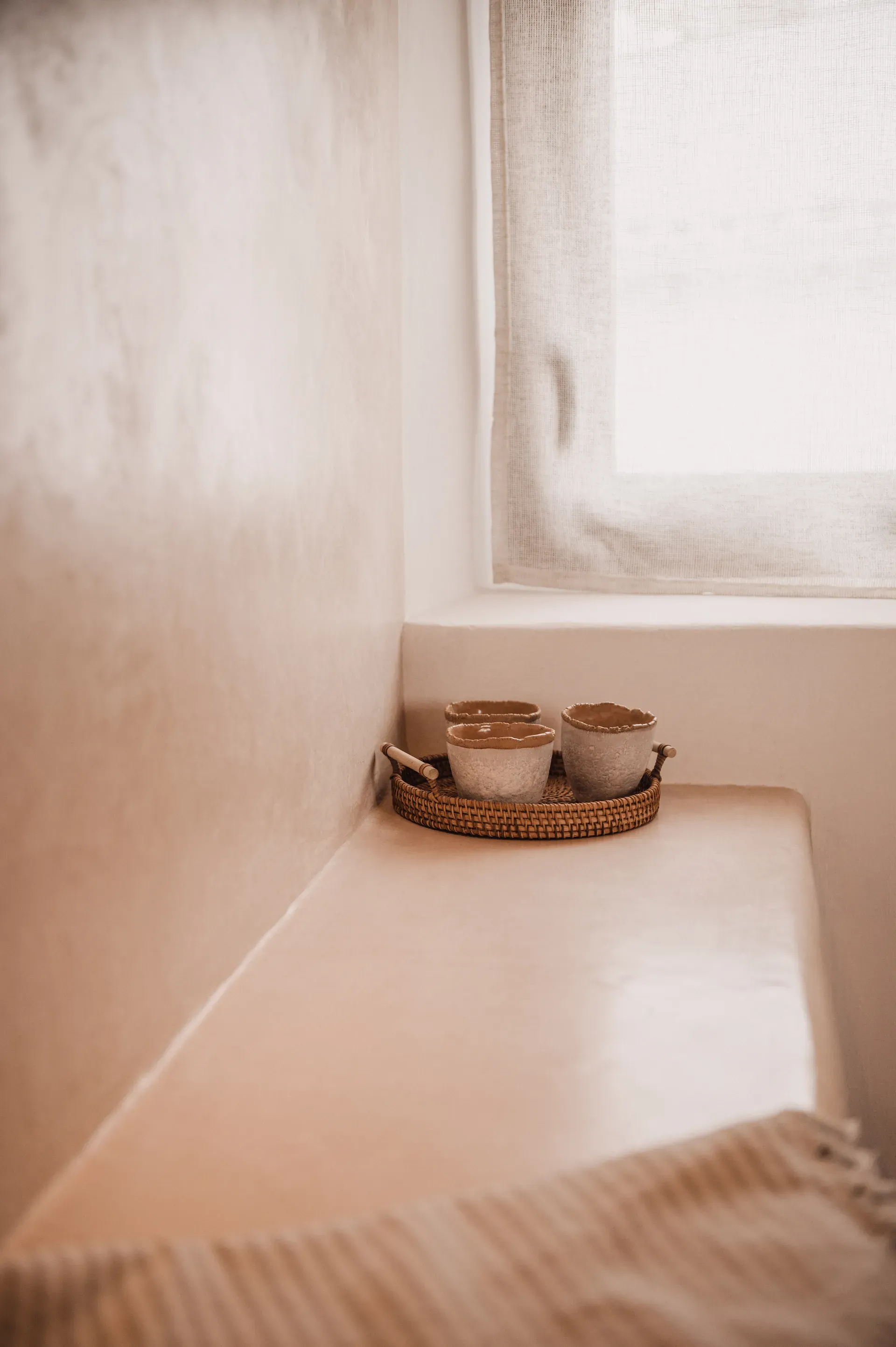 Detalle de cuencos de cerámica artesanal sobre banco de tadelakt bruñido iluminado por luz natural