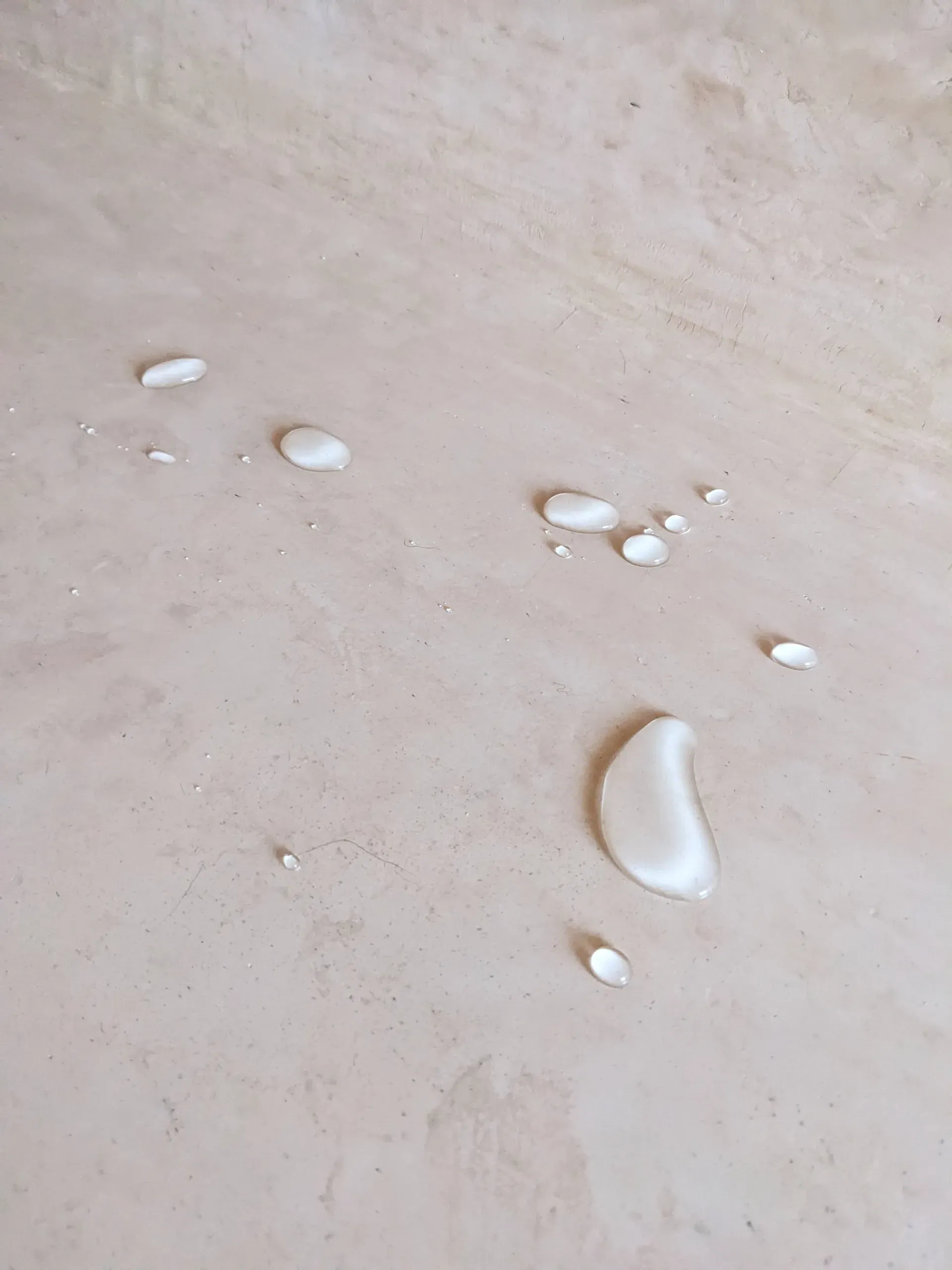 Primer plano de gotas de agua sobre superficie de tadelakt, demostrando la impermeabilización con jabón negro y cera