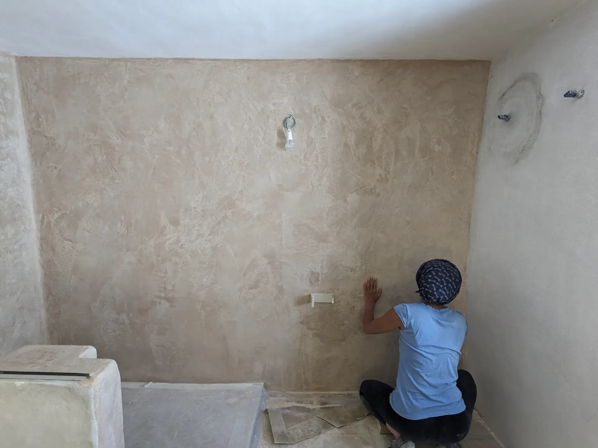 Proceso de aplicación artesanal de tadelakt en pared, mostrando la técnica manual de acabado