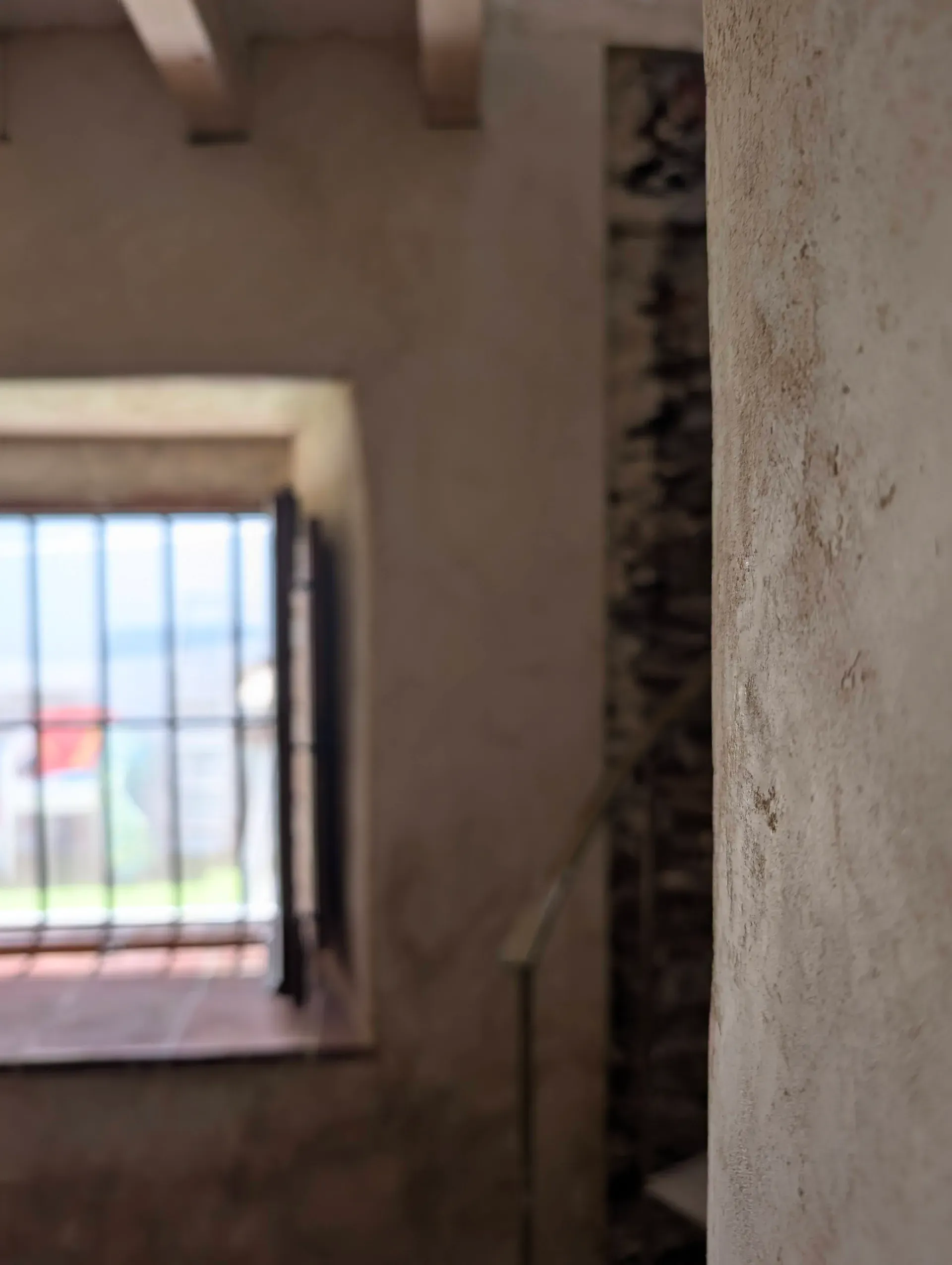 Detalle de encuentro entre muro de mampostería y revestimiento de cal en ventana con rejería tradicional