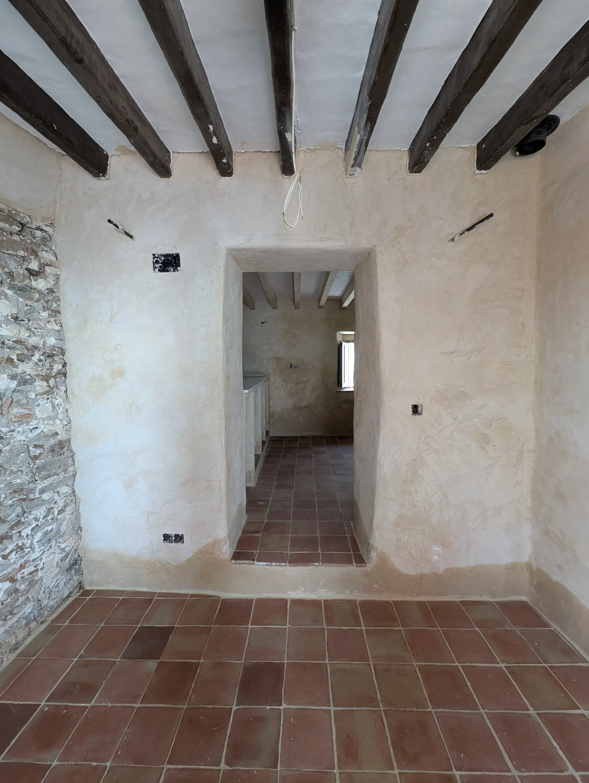 Estancia principal rehabilitada con suelo de barro artesanal, techos de madera y muros tratados con mortero transpirable